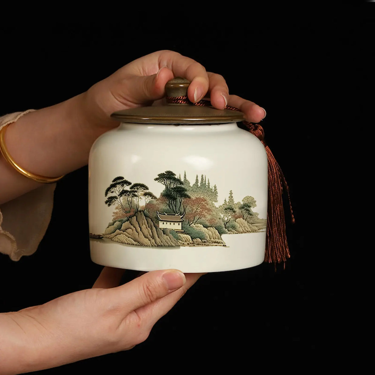 Elegant Bi Luo Chun green tea ceramic jar with traditional Chinese landscape painting, featuring an airtight lid and decorative tassel. Perfect for storing premium Chinese tea or as a unique gift for tea lovers.
