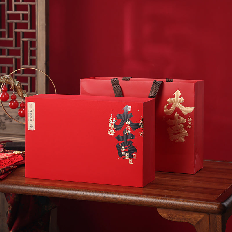 Premium Yunnan Dian Hong black tea gift box and matching red gift bag with gold Chinese calligraphy, perfect for presenting authentic Chinese black tea during holidays, celebrations, and special occasions.

